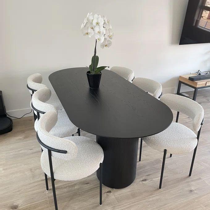 Aria Boucle Dining Chairs arranged around a modern black dining table, featuring off-white boucle fabric and powder-coated steel legs, perfect for elegant dining rooms.